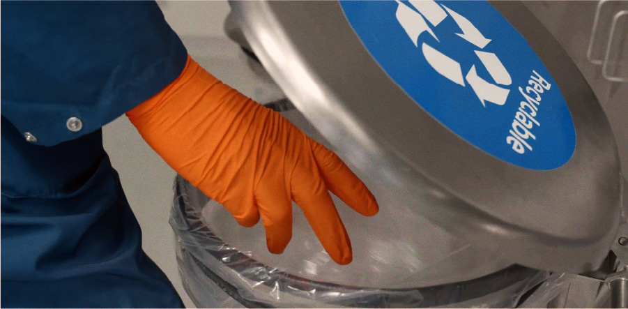 Orange gloved hand reaching into recycling bin