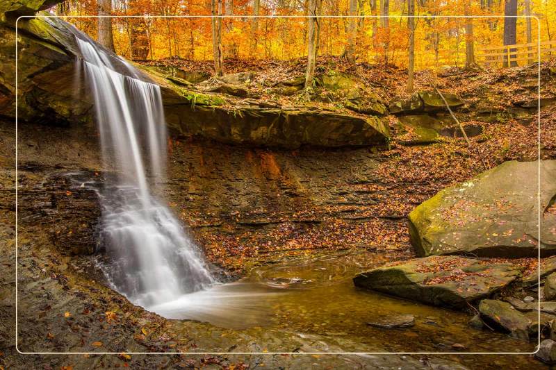 a waterfall among fall foliage at Cuyahoga Valley National Park, a dog-friendly national park where one can go hiking with dogs