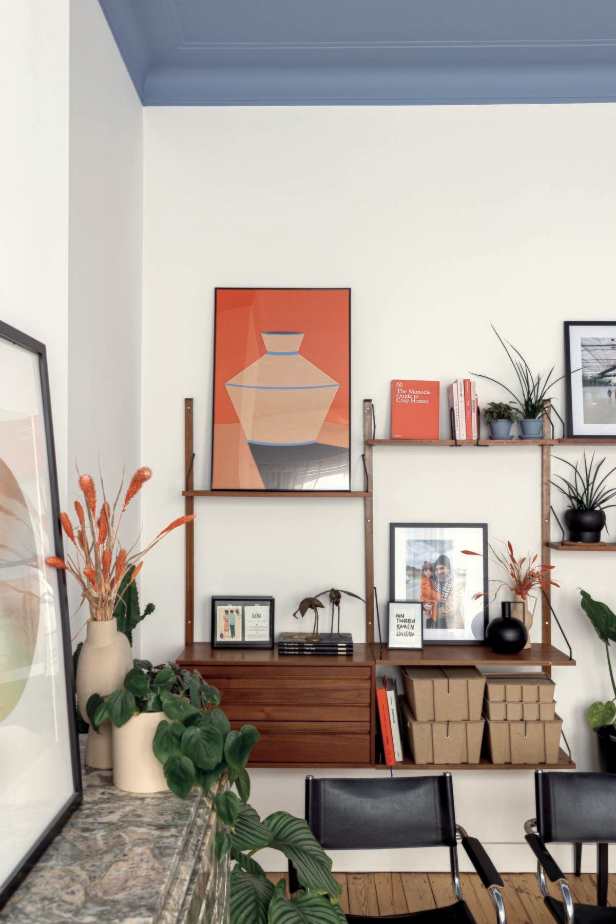 colora - woonkamer met witte muren, blauw plafond en houten kast met zwarte stoelen - magazine herfst 2022