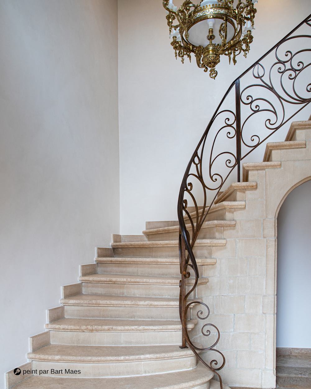 Escalier en pierre élégante avec rampe ornée et lustre
