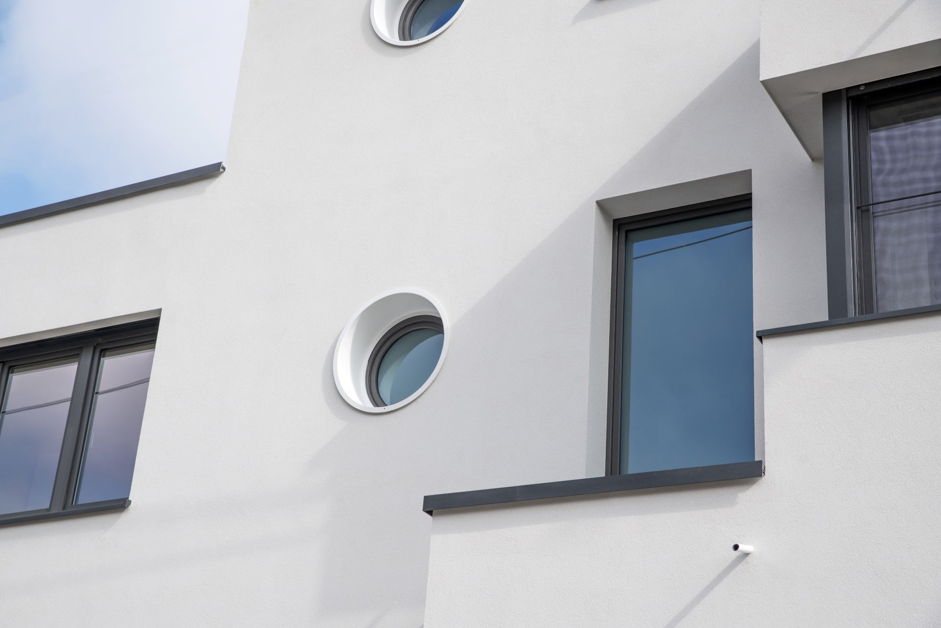Gros plan sur le côté droit d'une maison blanche avec des fenêtres rondes et carrées