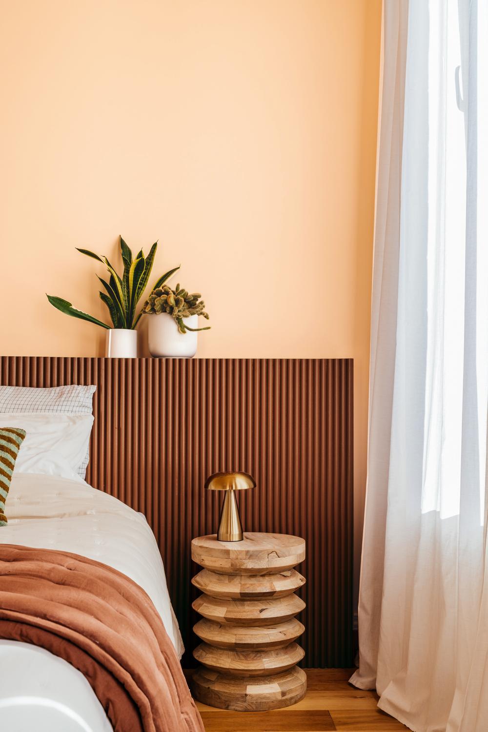 Les plantes et la table d’appoint en bois apportent une touche fraîche et vivante. La lampe dorée ajoute une note d’élégance.