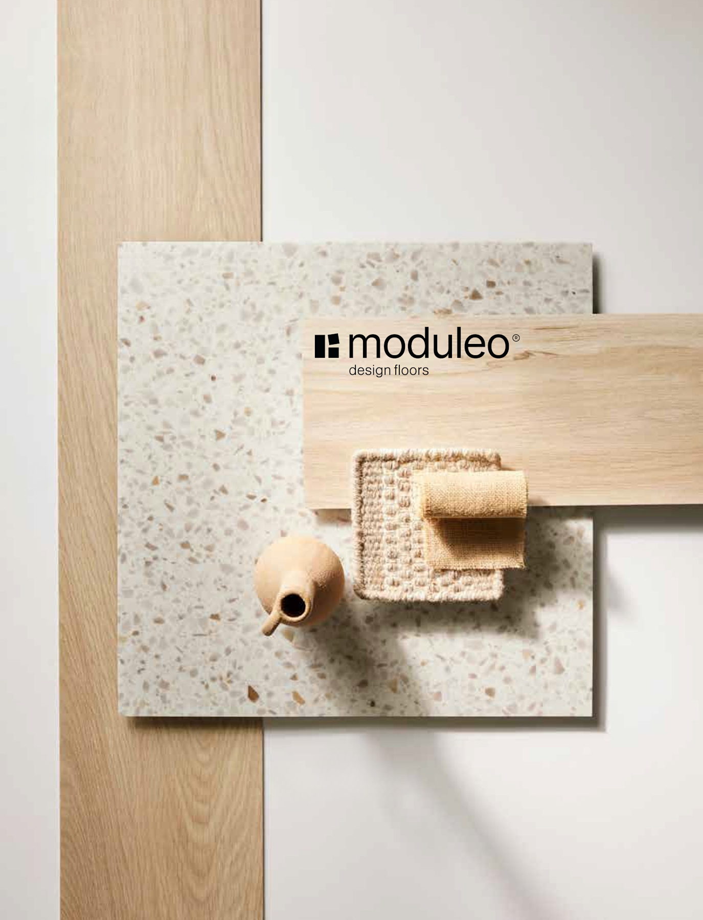 Op de flat lay zijn een terrazzotegel, lichte houten planken, een klein vaasje, een geweven matje en een opgevouwen doek te zien, allemaal gerangschikt op een witte achtergrond. Onderaan staat het logo van Moduleo Design Floors.