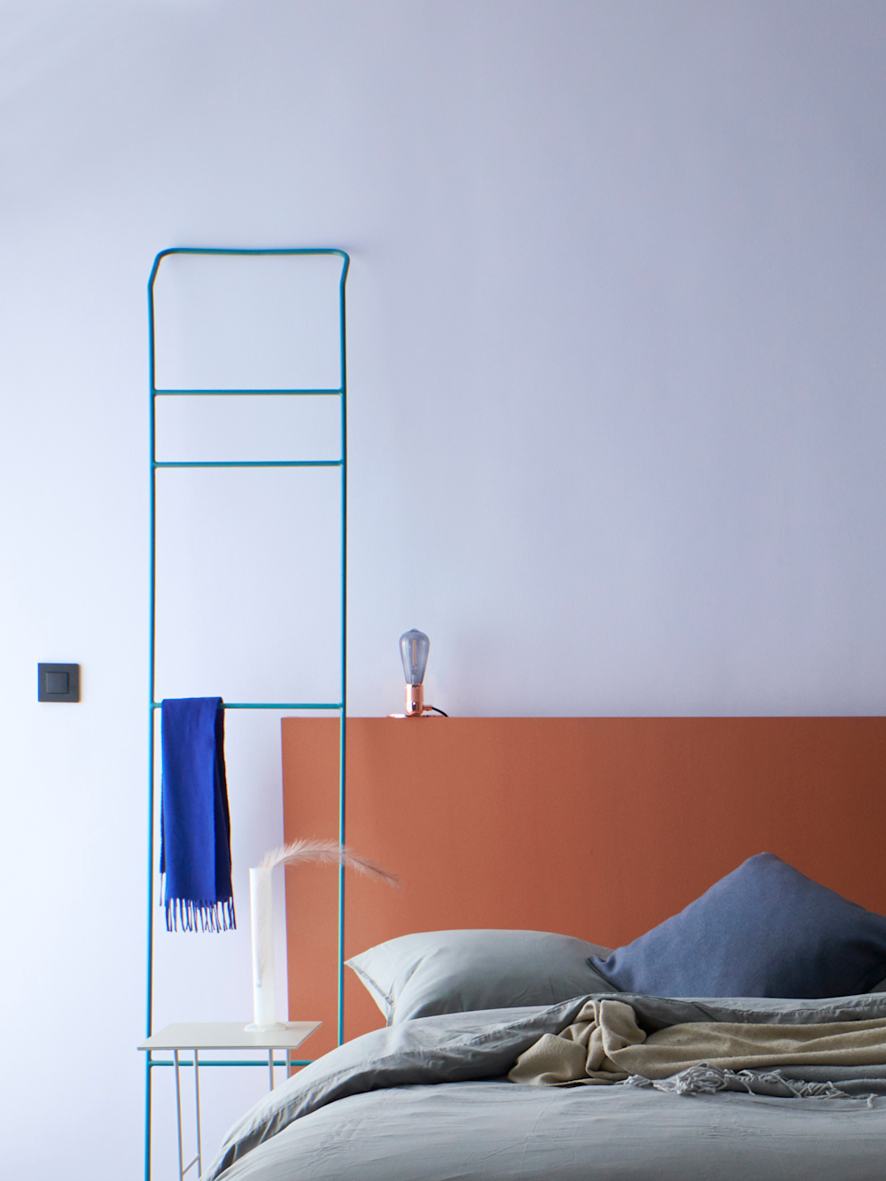Colora-slaapkamer met lichtblauwe muur achter het bed en hoofdeinde in het oranje