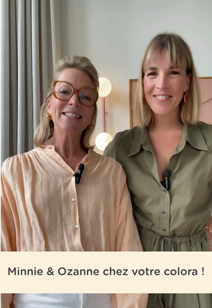Deux femmes (Ozanne et Guillemine Mertens) se tiennent côte à côte dans un magasin et sourient à la caméra, avec le texte : « Minnie & Ozanne dans votre colora ! »
