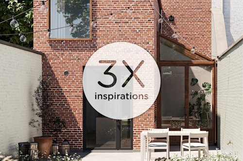 Une maison moderne en briques rouges avec de grandes fenêtres et des portes vitrées s'ouvre sur un patio. Au-dessus d'une table à manger blanche avec quatre chaises sont suspendues des lampes d'extérieur. Des plantes en pot décorent la pièce. 