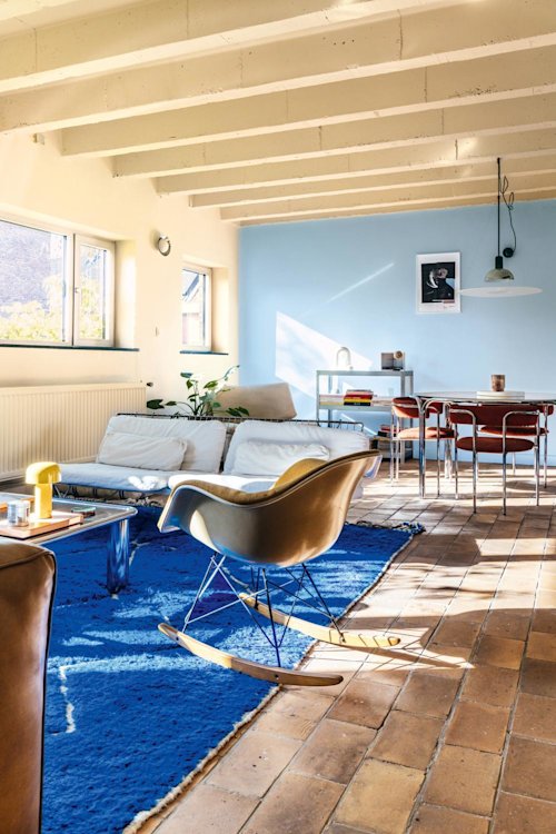 Een man en een vrouw staan samen binnen bij een raam en glimlachen naar elkaar. De man legt zijn arm op de schouder van de vrouw.