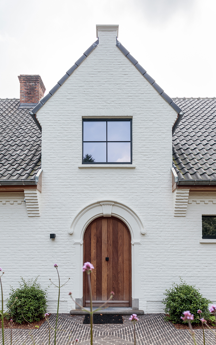 Decoratieve techniek toegepast op een huis met houten deur en gladde, matzwarte ramen. Op de gevel is een kalei-look toegepast met Pastime in witte kleur. 