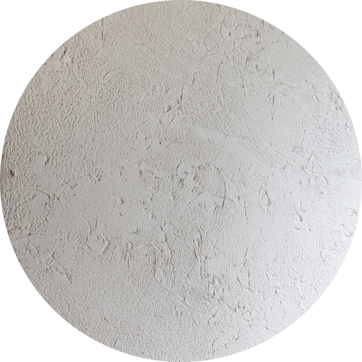 Une tache circulaire de crépi texturé blanc, présentant des motifs rugueux et irréguliers ainsi que de subtils tourbillons, sur un fond uni.