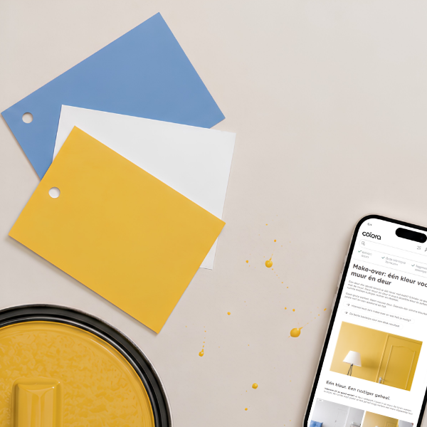 Op een neutraal oppervlak liggen drie verfstalen (blauw, wit, geel), een verfblik met gele verf, gele verfspatten en een smartphone waarop een website over verf te zien is.