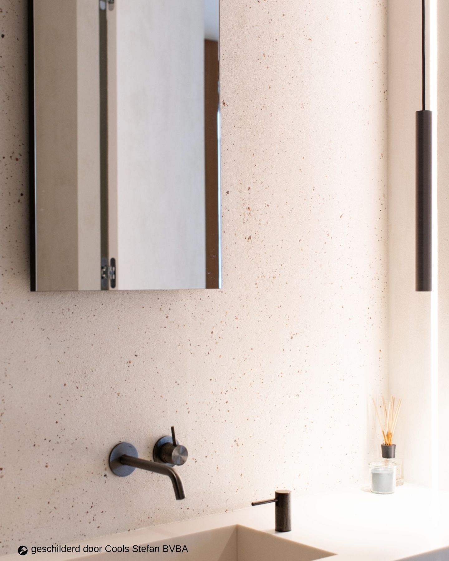Accentmuur in Stone Art Terrazzo met een spiegel en witte wasbak in de badkamer