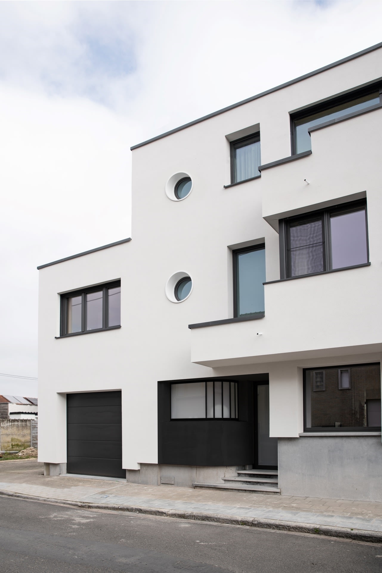 Maison mitoyenne blanche et élégante avec des fenêtres noires et un garage