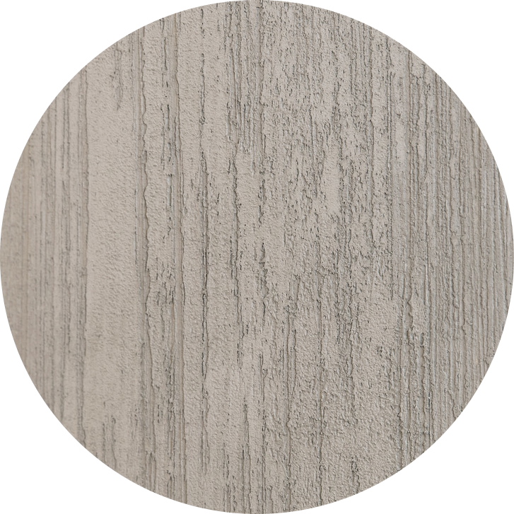 Un échantillon circulaire présentant une surface grise texturée, réalisé selon la technique de peinture décorative Calco Vintage Decay