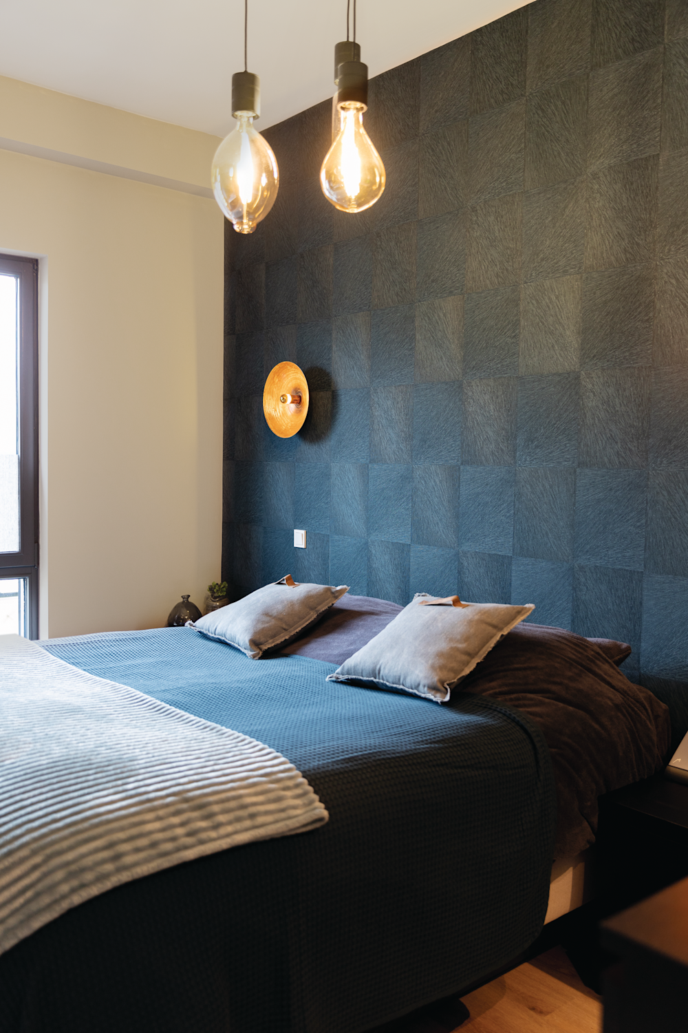 Colora-slaapkamer met witte muren en accentmuur achter het bed met blauw motief in behangpapier