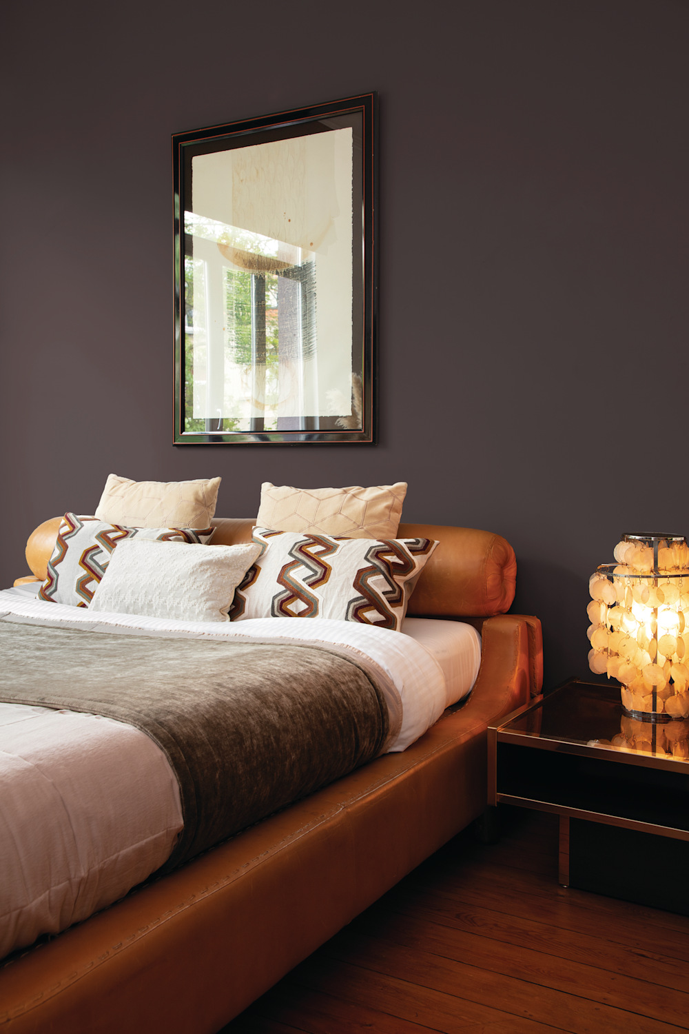 Colora-slaapkamer met donkerbruine accentmuur achter het cognackleurig bed en lamp