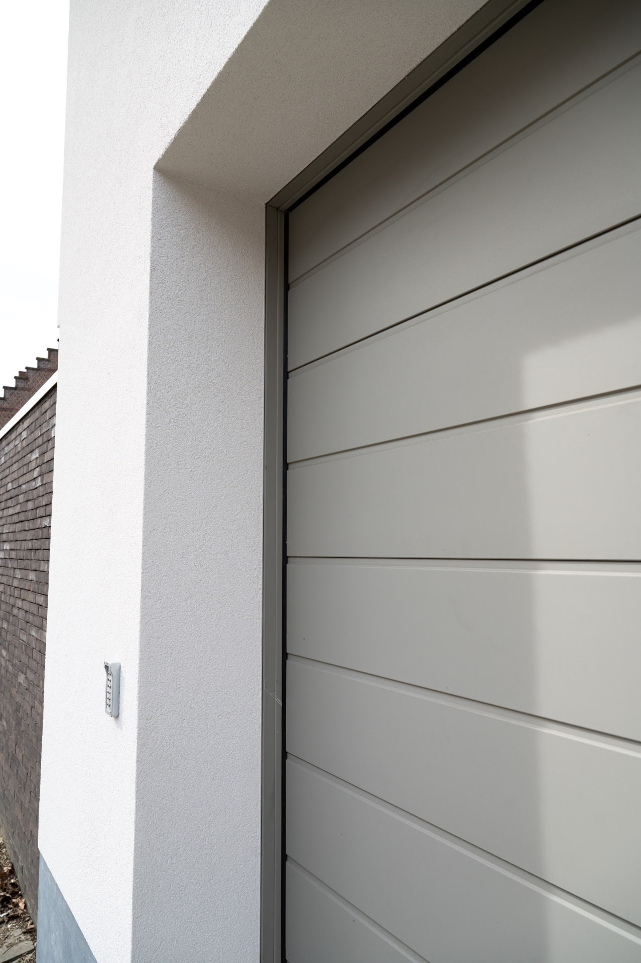 Une porte de garage grise entourée d'un mur blanc