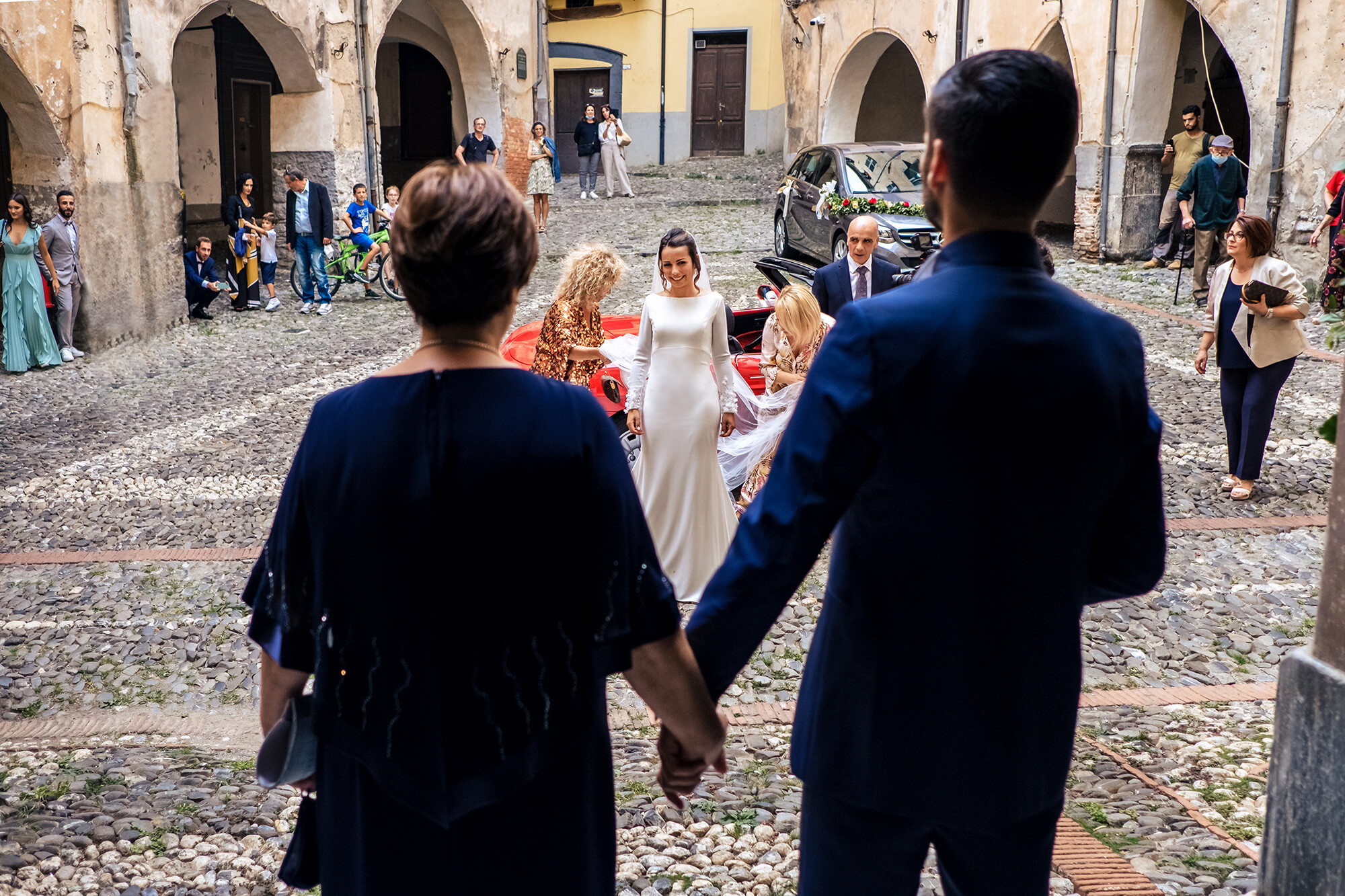 una foto di matrimonio ad Arma di Taggia, in provincia di Imperia, la sposa arriva davanti alla chiesa e lo sposo la aspetta.