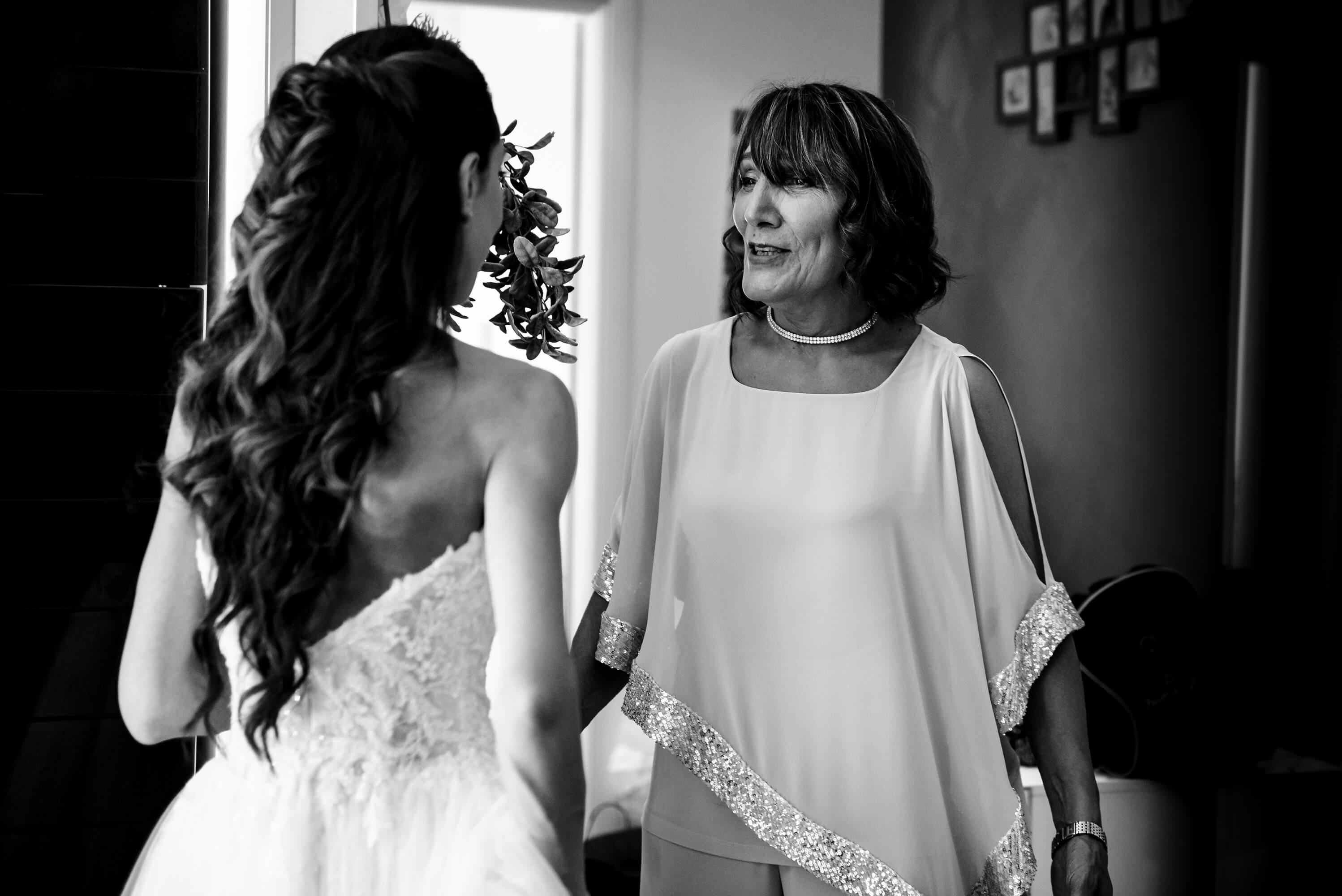 una foto della mamma della sposa che guarda emozionata la figlia con l'abito da sposa.