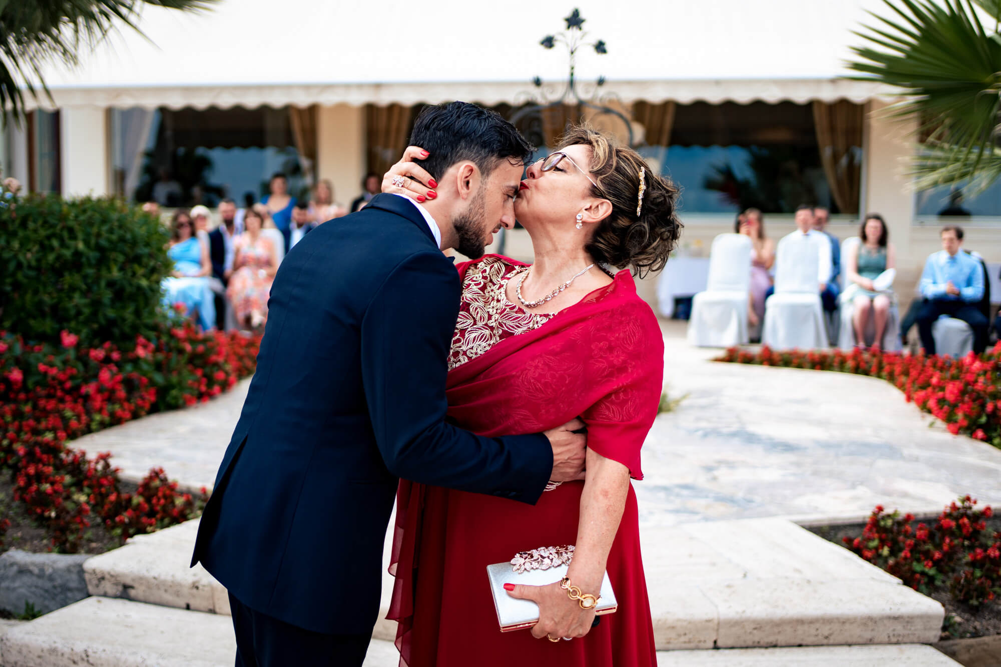 la mamma da un bacio sulla fronte allo sposo dopo l'ingresso sulla terrazza dell'hotel royal dove è stato celebrato il matrimonio.