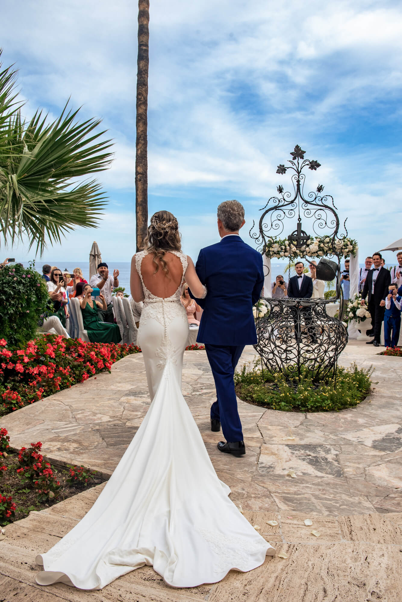 una foto dell'abito da sposa fotografato da dietro durante l'ingresso della sposa alla cerimonia di matrimonio.