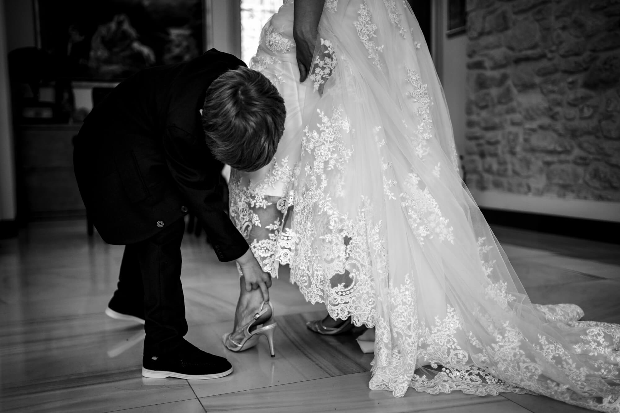 la sposa che infila le scarpe del matrimonio aiutata dal figlio, a Sanremo.