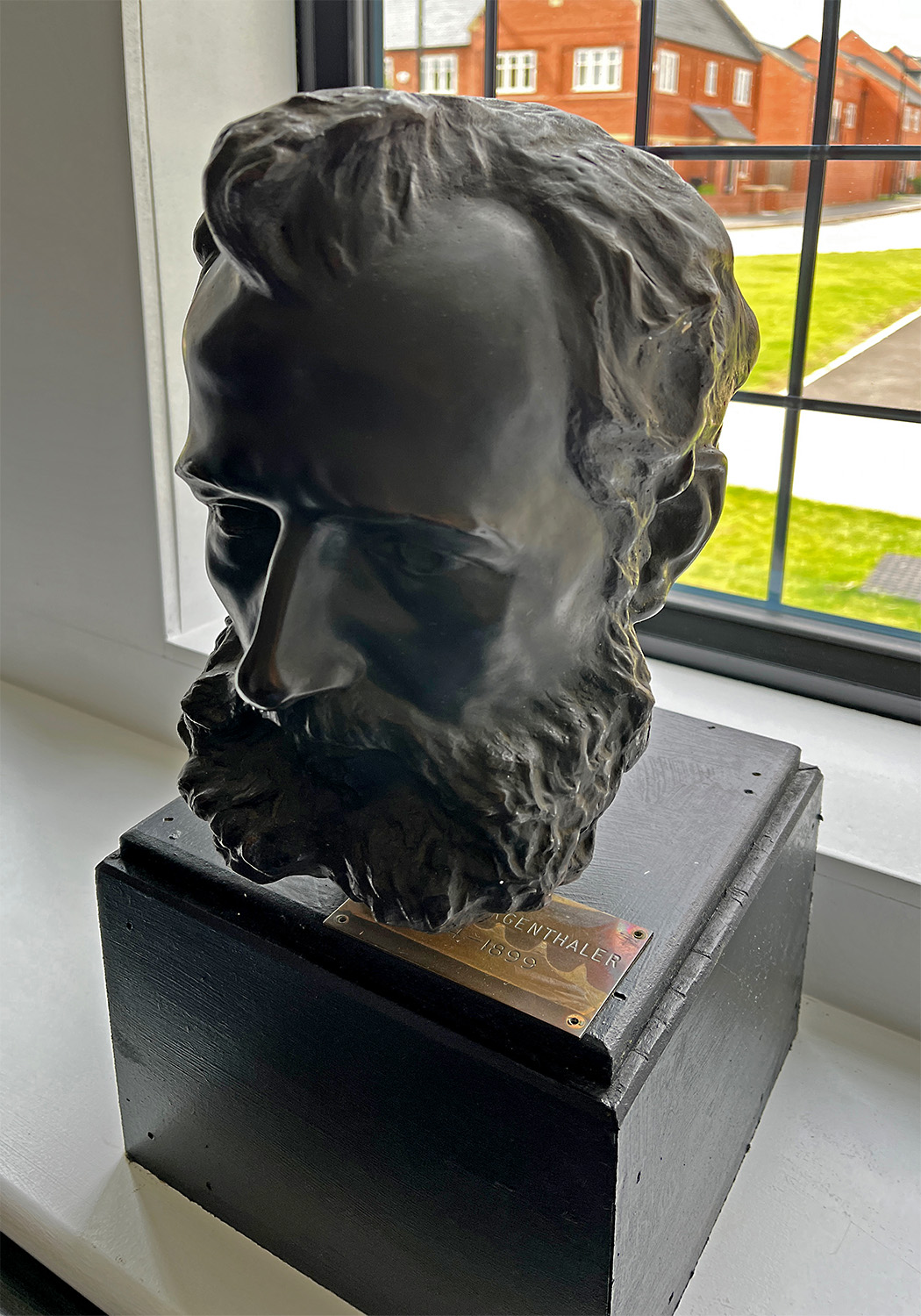A small statue of Ottmar Mergenthaler hangs out on a window sill.