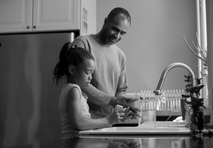 man helping a child wash her hands