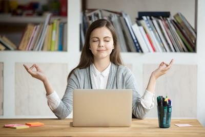 A woman practising meditation at her work desk. A woman practising meditation at her work desk.