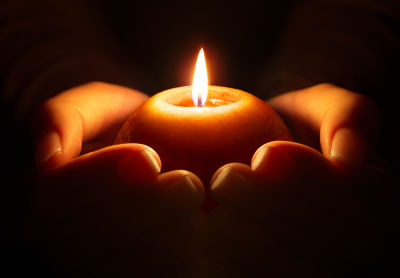 A picture showing hands holding a lit candle. A picture showing hands holding a lit candle.