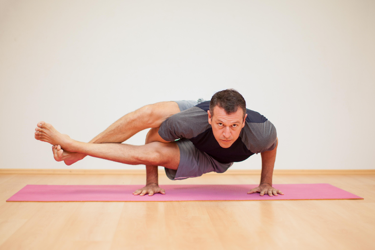 A man practising the Astavakrasana or the eight angle pose.