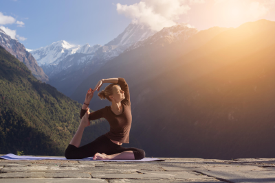 A woman practising yoga at a scenic location.