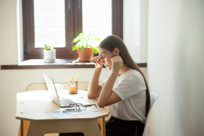 A woman sitting at the desk with her laptop looking stressed. A woman sitting at the desk with her laptop looking stressed.