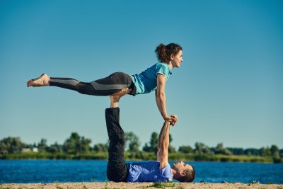 Man supporting woman in an advance yoga pose 