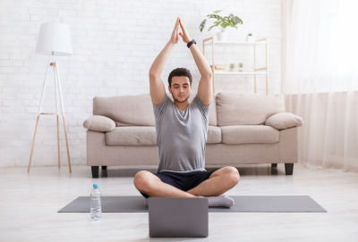 A man sitting in sukhasana with palms joined above his head. A man sitting in sukhasana with palms joined above his head.