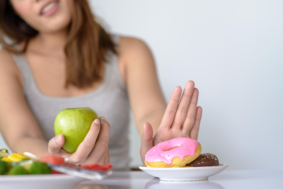 A woman choosing healthy food over junk food.