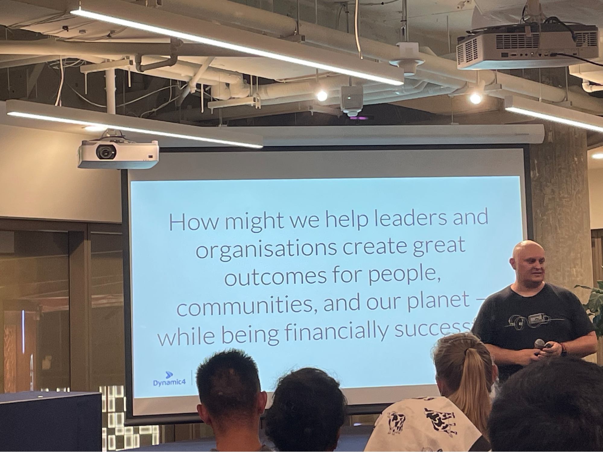 A photo from an event showing a slide about how might we help leaders and organisations create great outcomes for people.