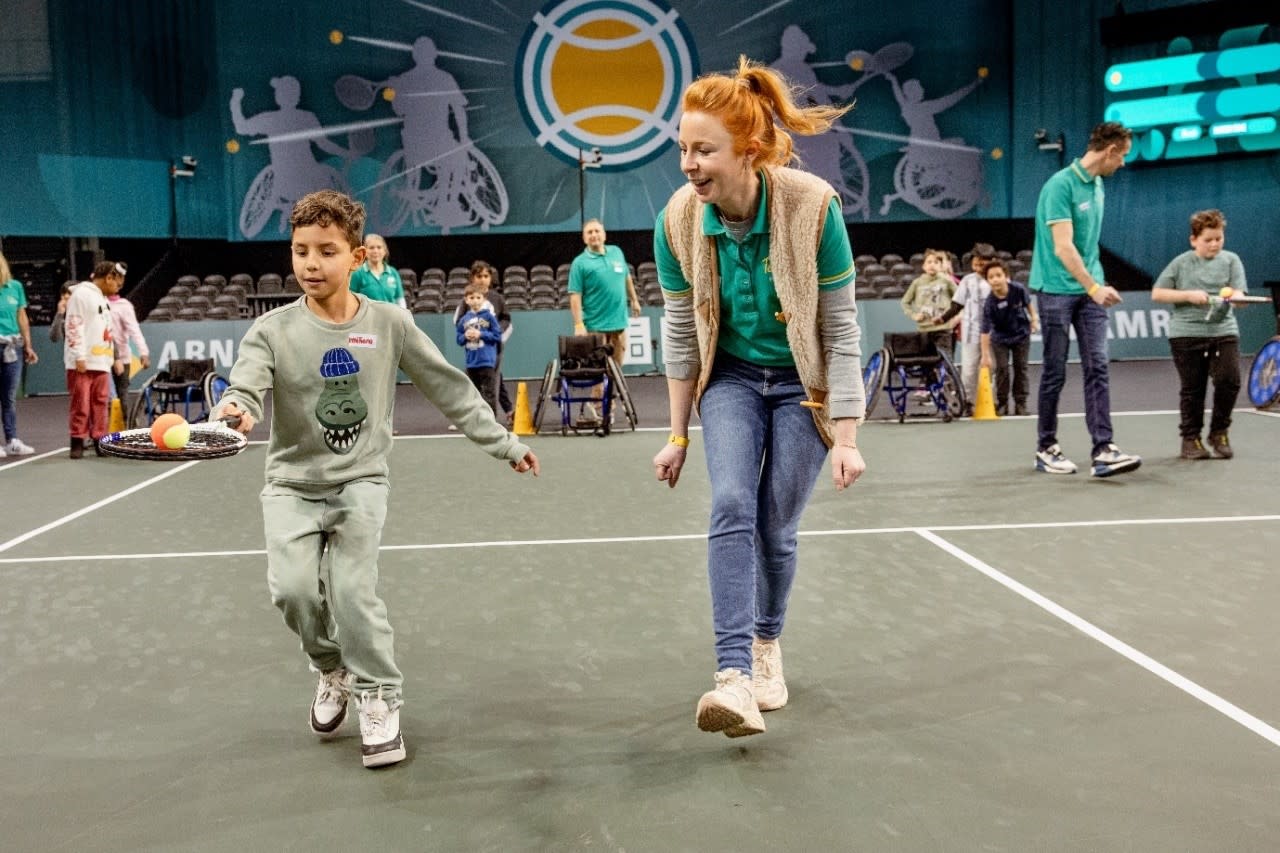 Kind met tennisracket en bal en begeleider op ABN AMRO open