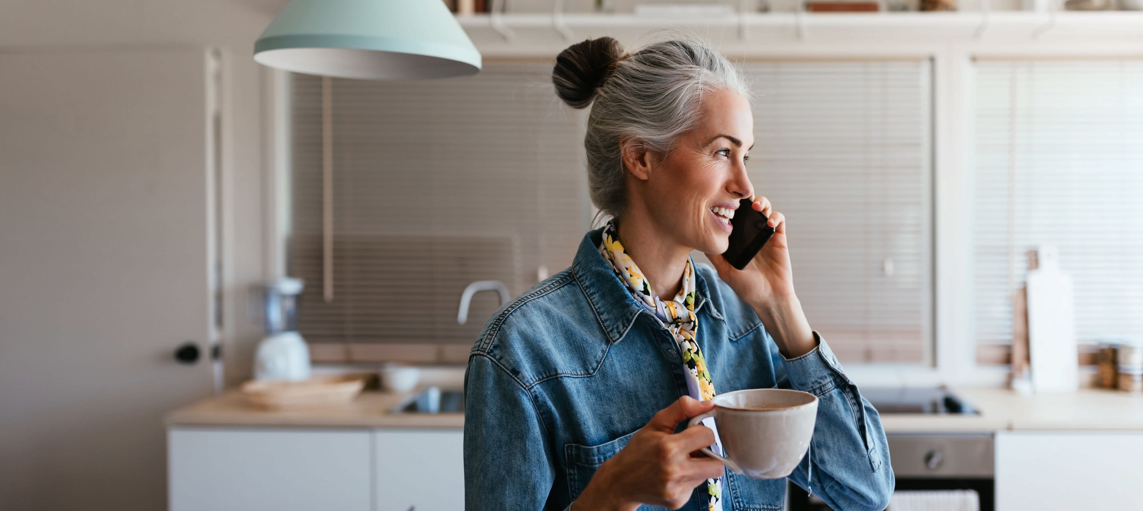 Vrouw aan de telefoon met kopje thee in haar hand