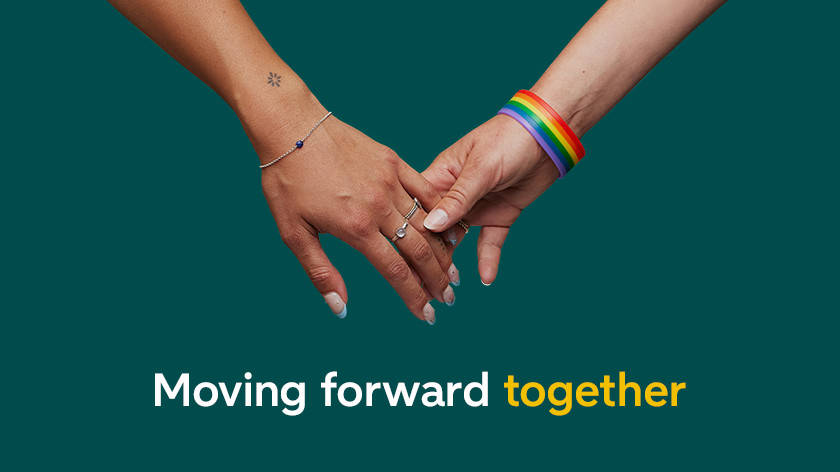 A white and a colored hand hold each other. Displayed is "moving forward together"