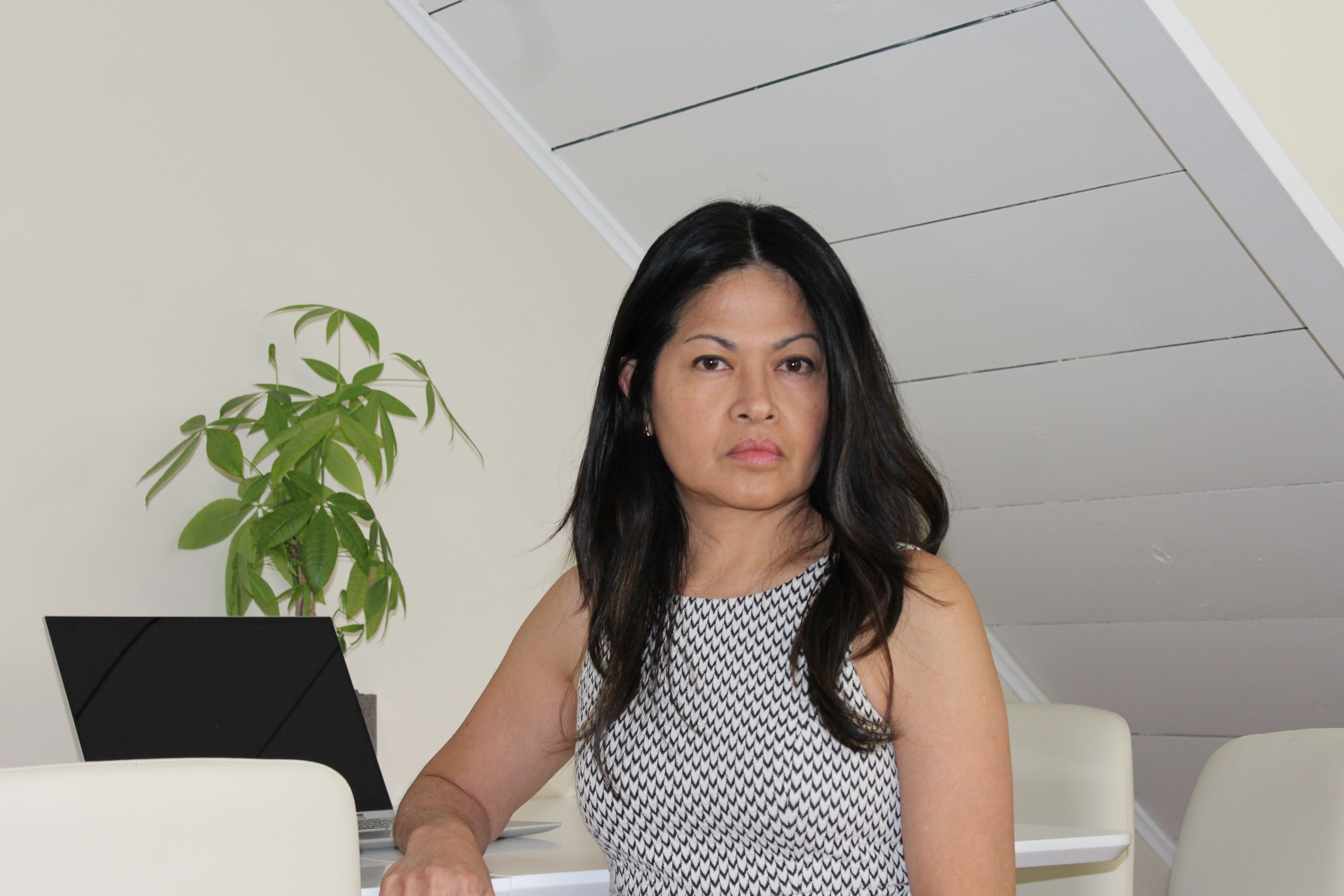 Woman wearing grey in loft room with plant.
