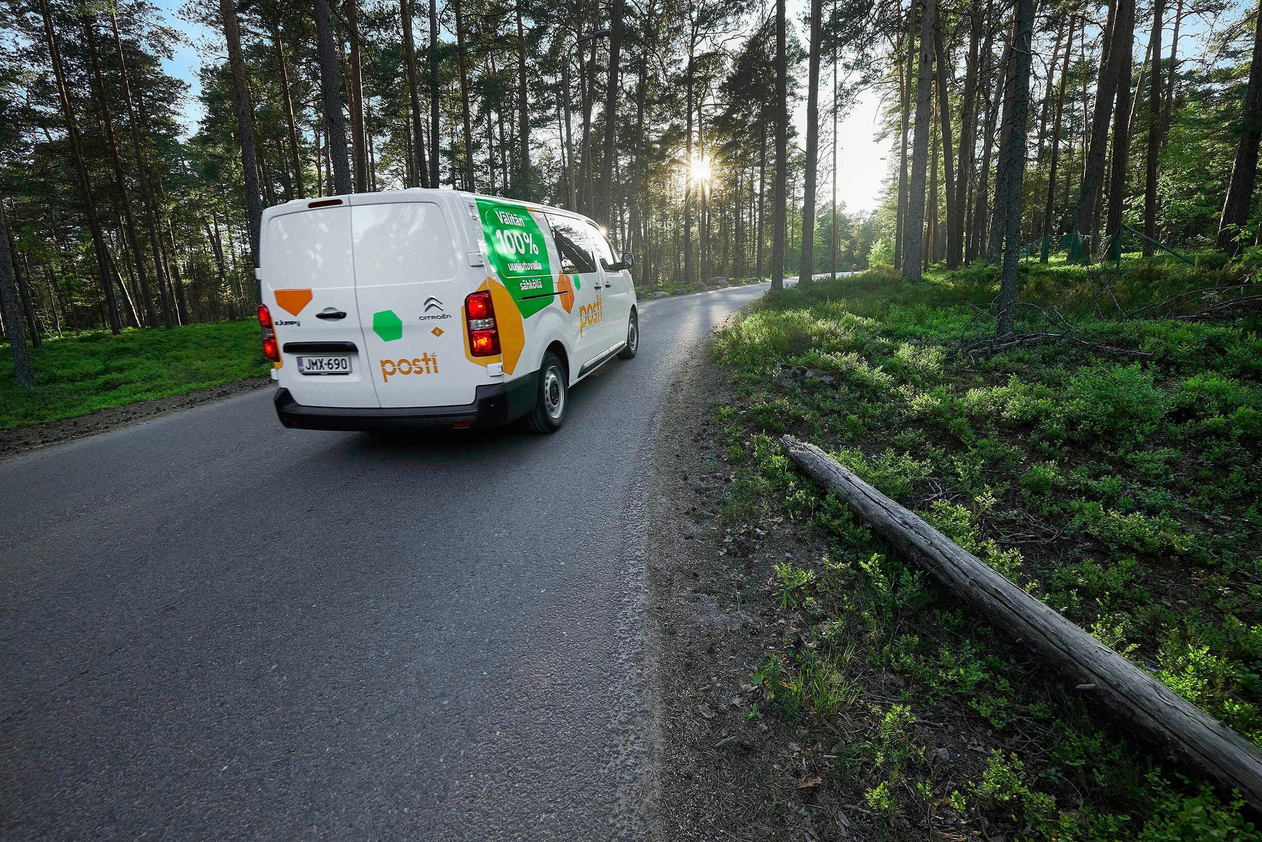 Postin pakettiauto ajamassa tiellä, joka kulkee halki metsän.