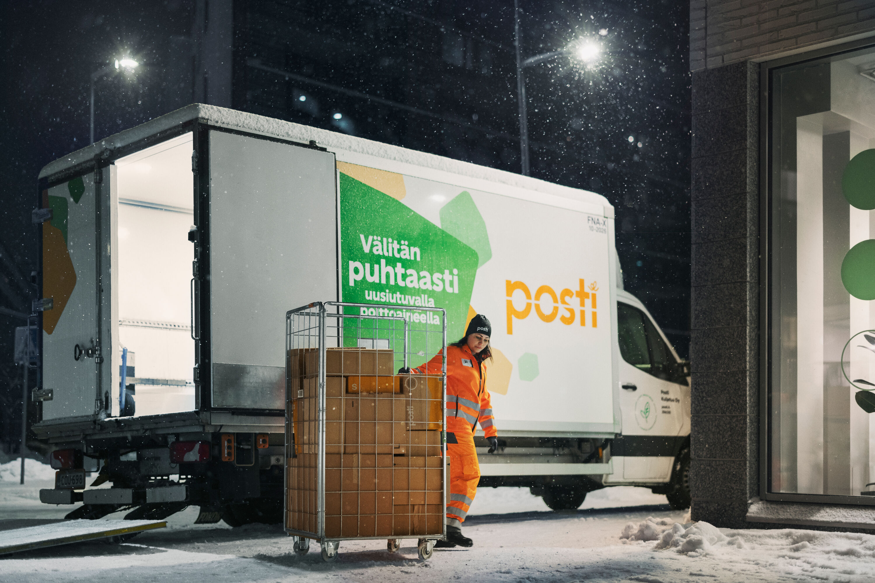 Posti employee pulls a trolley parcels from a freight van.