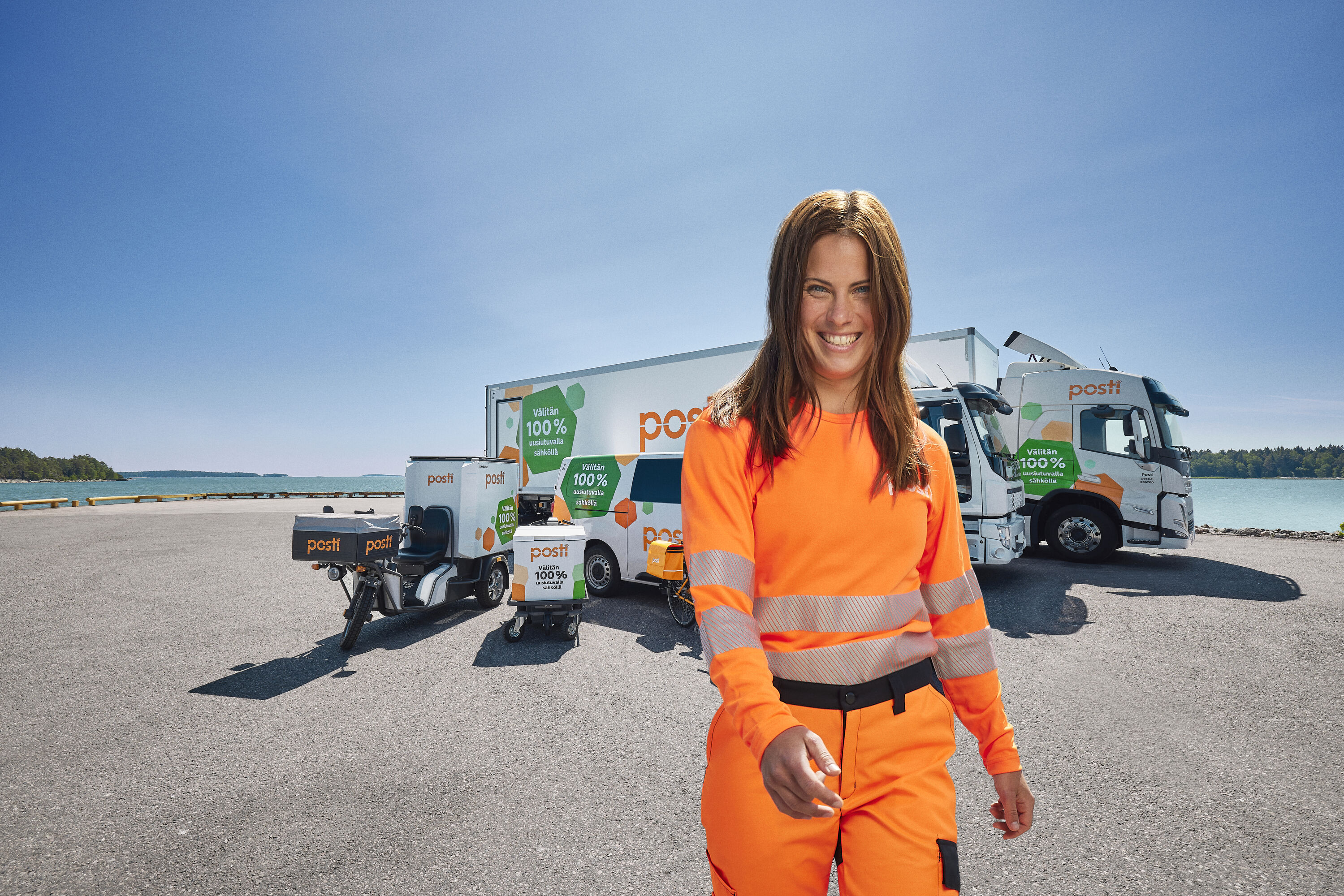 A woman in front of Posti's delivery vehicles