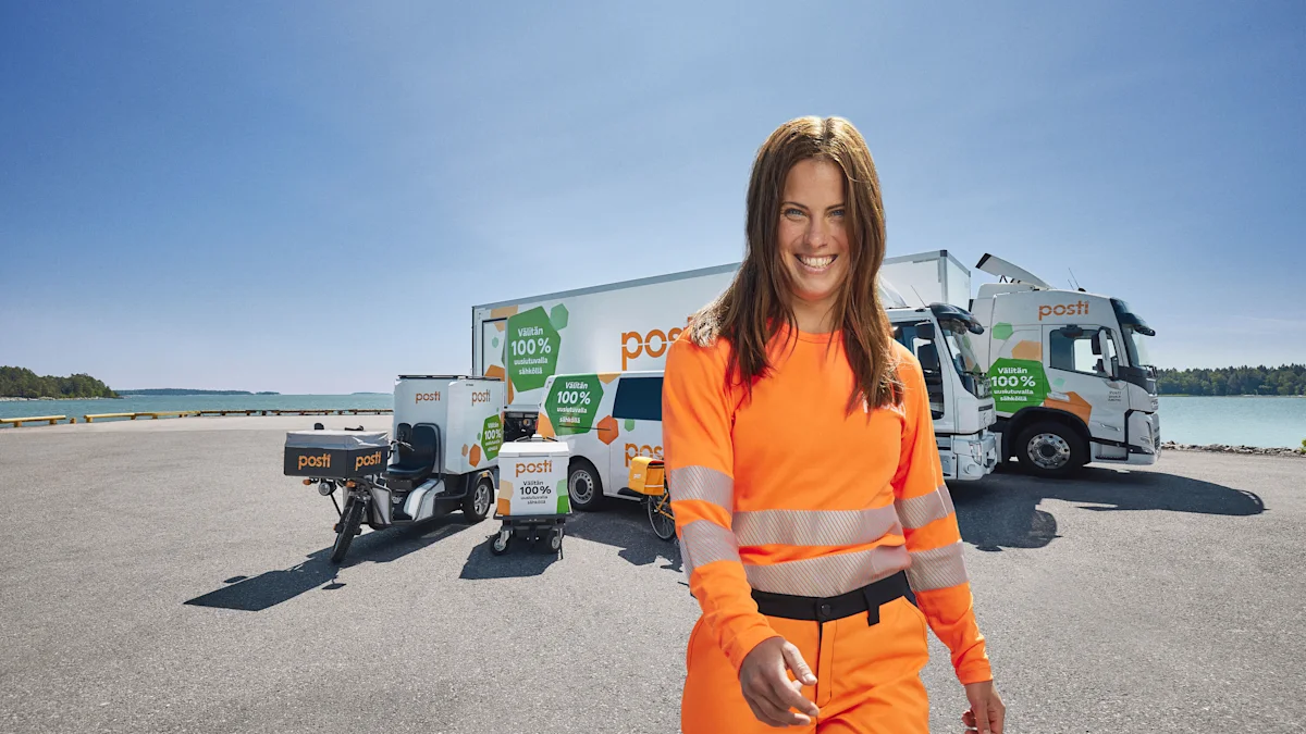 A woman in front of Posti's delivery vehicles