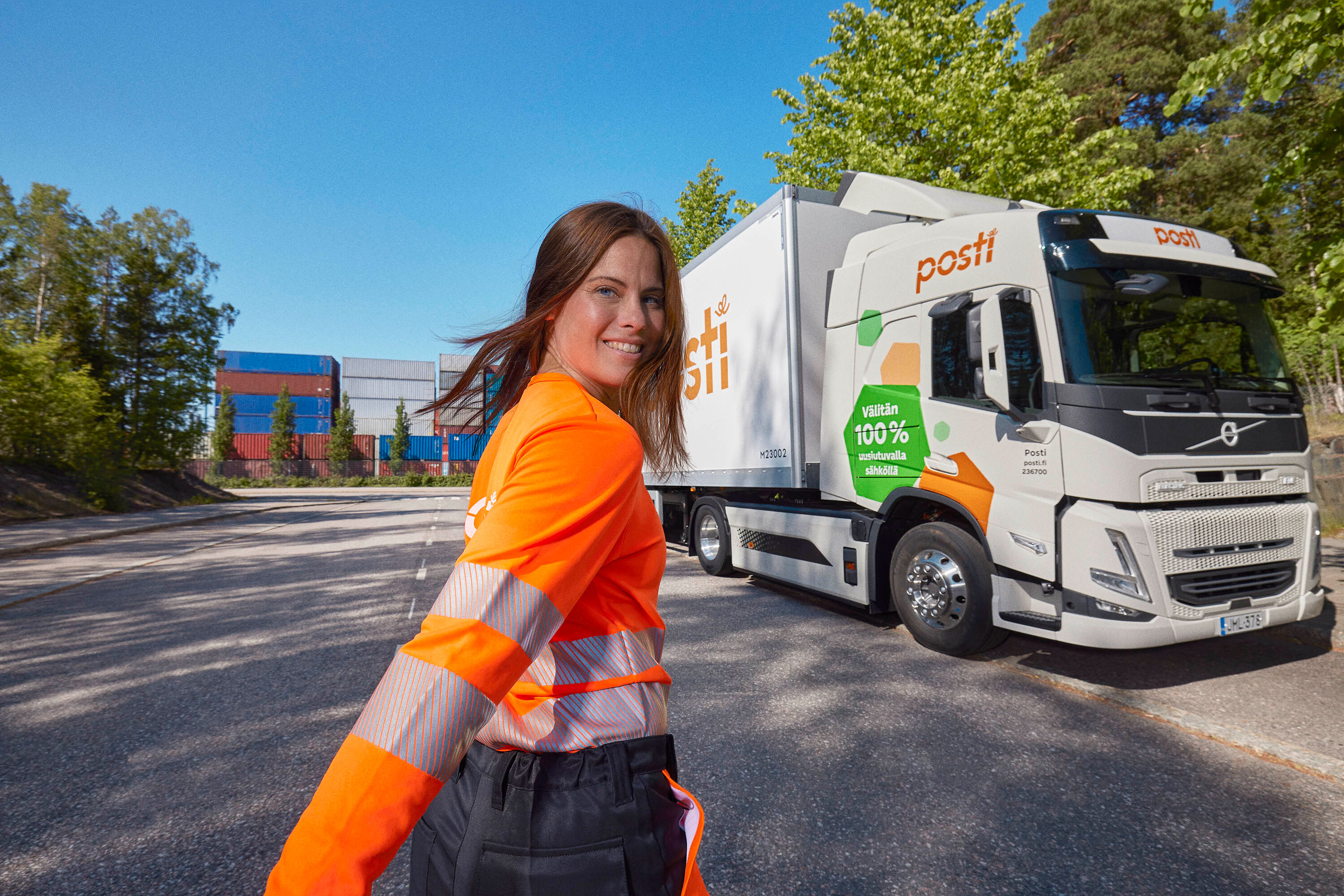 A smiling woman and a postal truck.