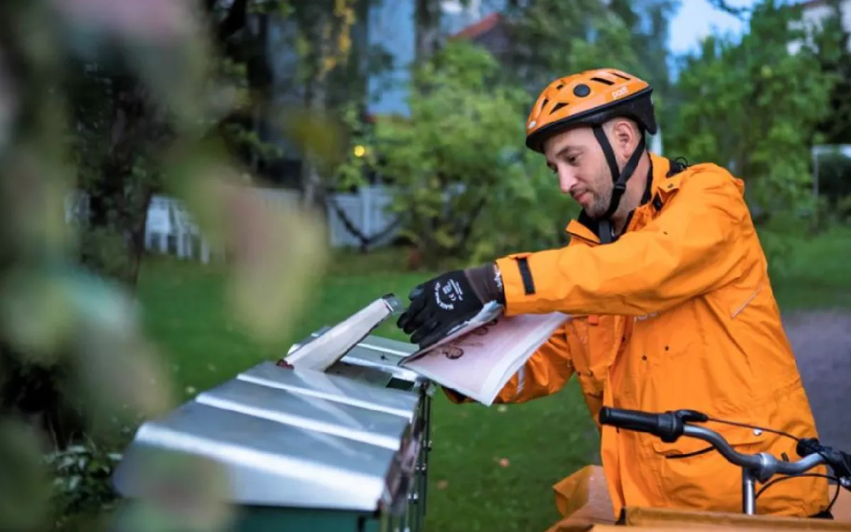 Mail delivery person delivering mail at a mailbox.