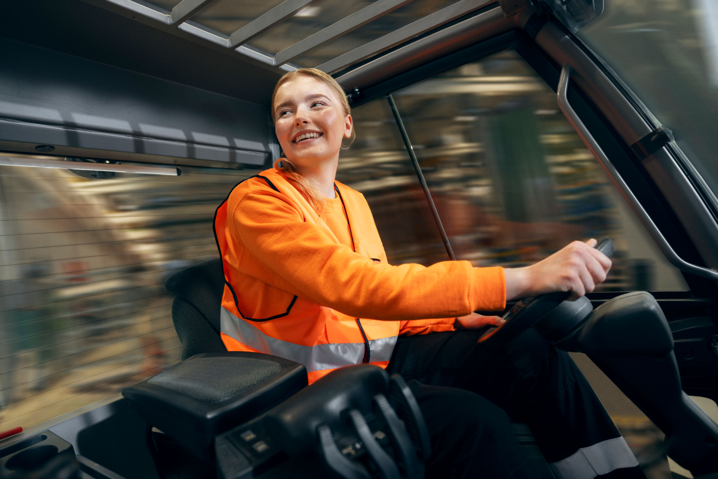 A happy Posti employee driving a forklift.