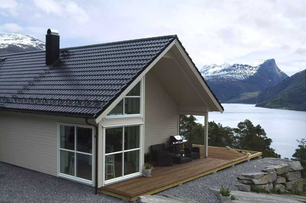 Hytte med Aerodek ståltakpanner som ser ut over en fjord. Takpannene er laget på en måte slik at de skal stå imot orkaner og nordisk hardt vær.