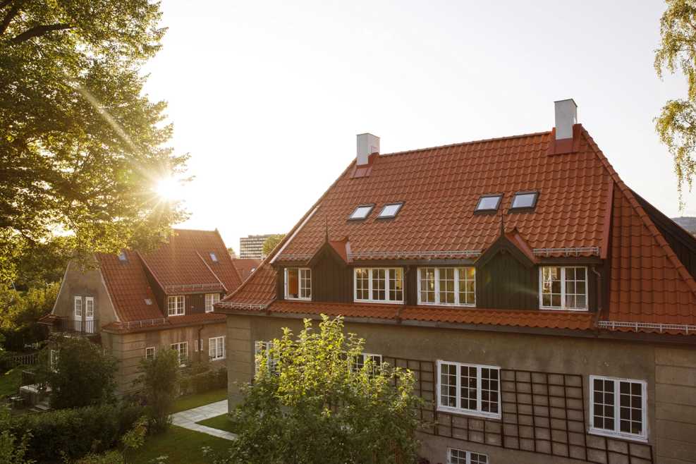 Solnedgang over et hus med Tegltaksteinen nortegl på. Et varmt bilde av et mursteinshus, med klassisk oransj tak i Ullevål Hageby.