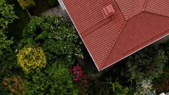 Dronebilde av hus med kdn lys brun tegltakstein og en fyldig hage